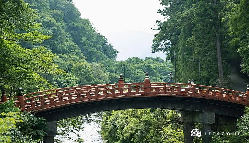 朱紅色的日光神橋橫跨溪谷,四周被茂密綠色森林包圍