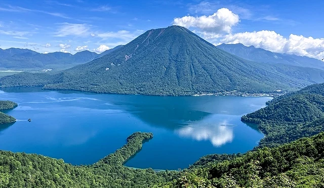 夏季的中禪寺湖全景,湖水湛藍清澈,遠方男體山聳立於湖畔,周圍群山覆蓋翠綠森林