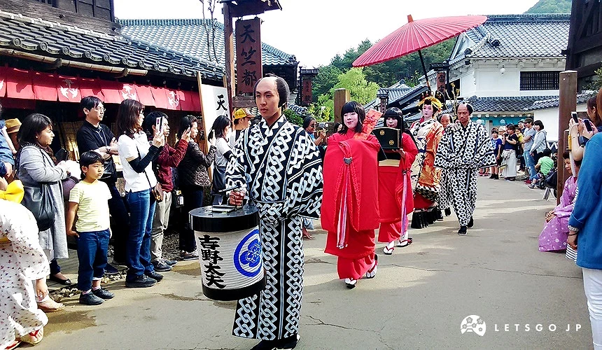 日光江戶村園區內的江戶時代遊行場景,演員身穿傳統和服服裝,沿著仿古街道行進,吸引遊客圍觀拍照