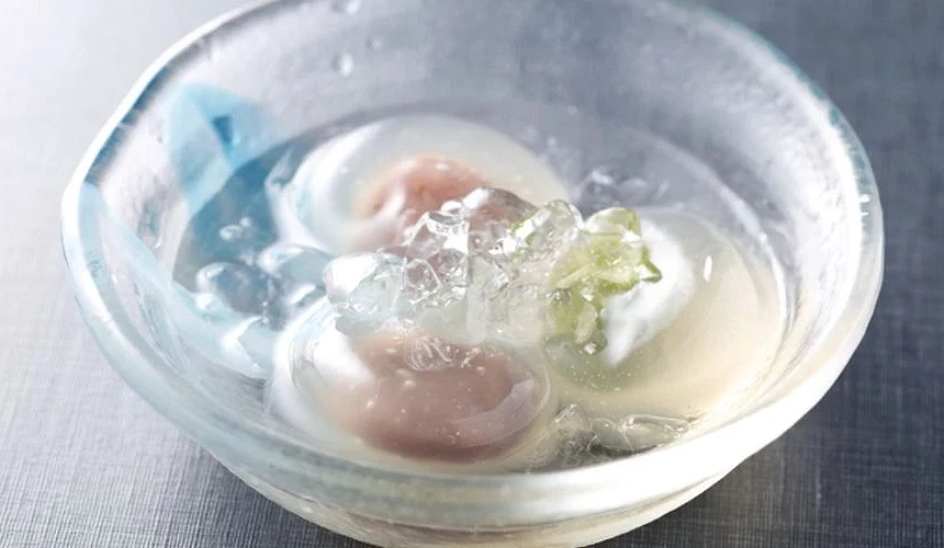 盛裝在透明玻璃碗中的郡上八幡名物「水饅頭」,粉嫩與白色的饅頭浸在清涼的冰水中,上方點綴碎冰