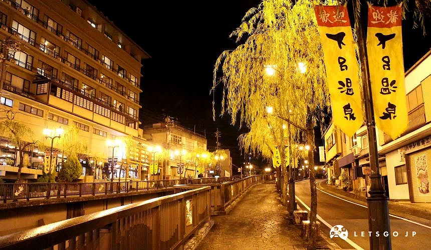 下呂溫泉的夜景,河畔步道在黃燈照映下顯得寧靜迷人,街邊掛有寫著「下呂溫泉」的旗幟
