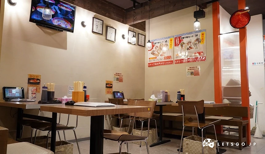 店內座位區,桌上放置平板、調味瓶,牆面貼有海報。