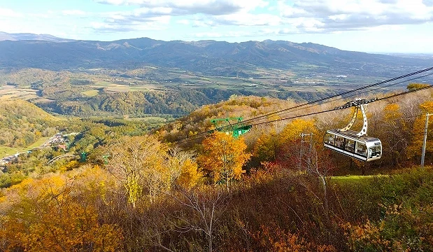 有珠山纜車秋季景色,纜車行駛於紅葉山林上方,遠方可眺望洞爺湖周邊地形與山谷平原
