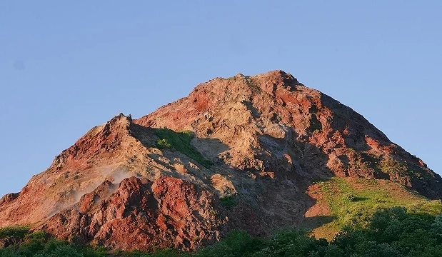 昭和新山紅褐色火山錐近景,裸露岩層與綠色植被交錯