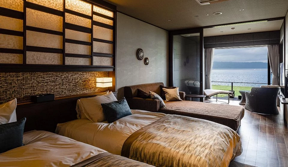 The Lake Suite 湖之栖客房內部,雙床房型搭配沙發休憩區,落地窗外可見洞爺湖湖景,呈現高級溫泉飯店氛圍
