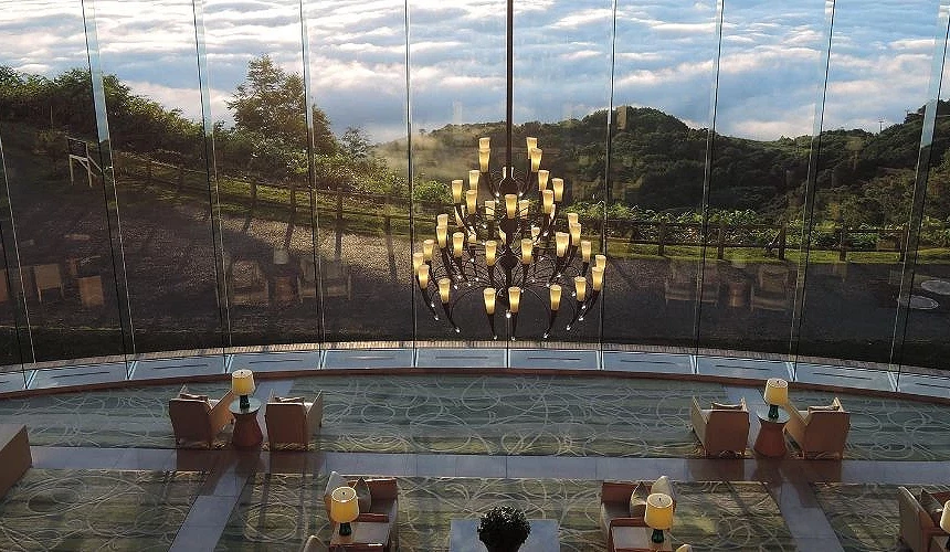 洞爺湖旅館內大廳空間,大片落地玻璃引入山林雲海景致,中央懸掛藝術感吊燈,座位區以溫潤色調營造靜謐優雅的度假氛圍