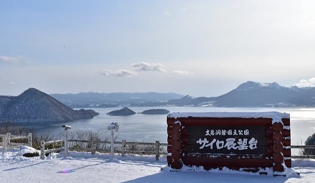 冬季筒倉展望台景色,前景為「サイロ展望台」木製標誌,背景可俯瞰覆雪的洞爺湖湖面與中島群島