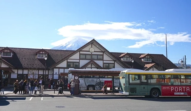 河口湖車站外觀與巴士站景色,前方停靠高速巴士,背景可見富士山山景