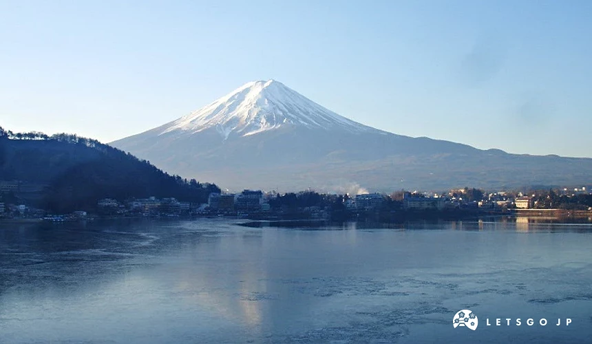 冬季河口湖湖畔遠望覆雪的富士山,湖面平靜映出淡淡山影