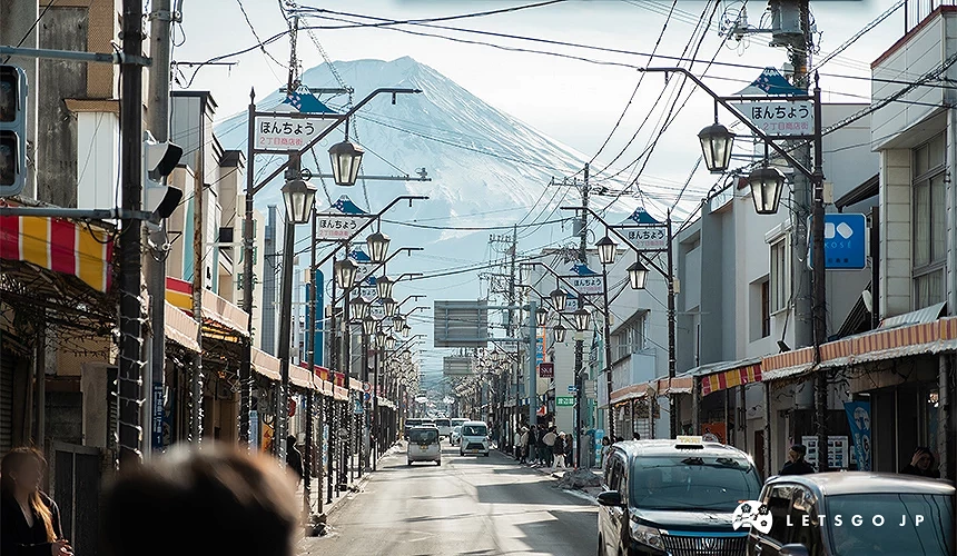 富士吉田市商店街街景,街道兩側林立店鋪,遠方可見富士山矗立其後