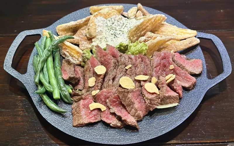 鐵盤盛裝切片牛排,搭配薯條與四季豆