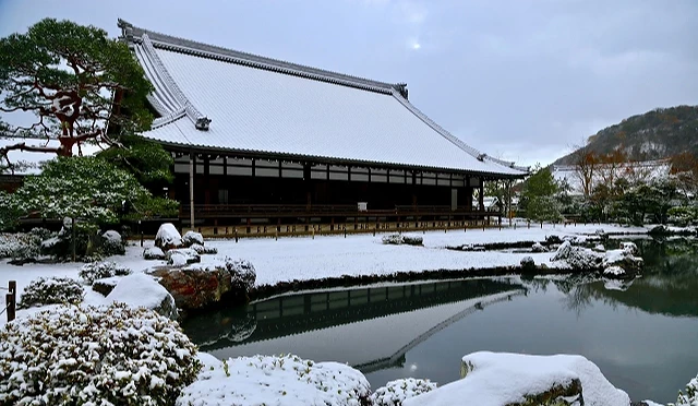 冬季的天龍寺曹源池庭園覆上一層白雪,法堂屋頂與庭園石景被積雪妝點