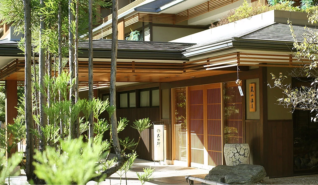 京都嵐山溫泉花傳抄的建築外觀,為結合木造格柵與現代日式設計的低調建築,入口被綠意環繞。