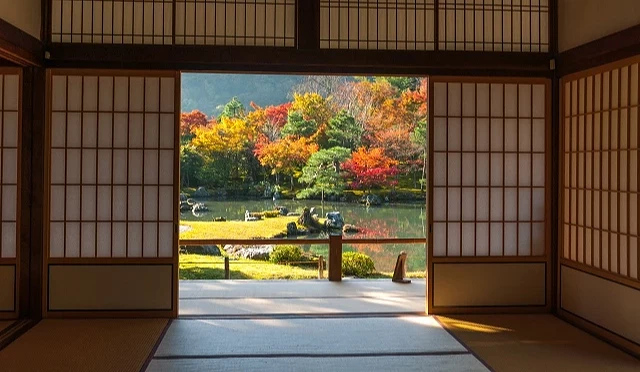 天龍寺室內視角拍攝曹源池庭園,拉門框出秋季紅葉與池塘景色