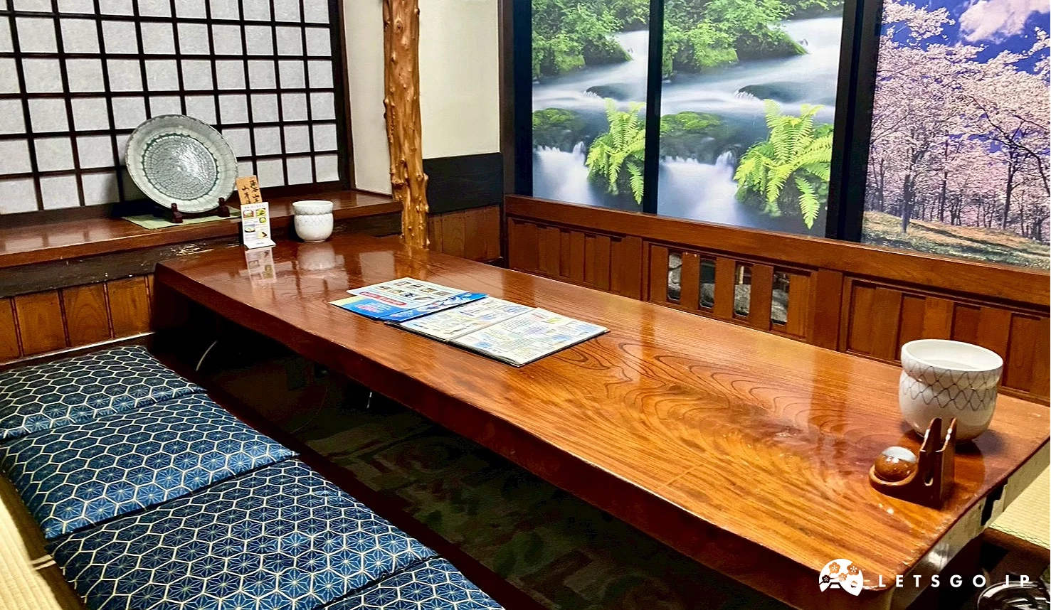 用餐桌位旁的牆面設有大型風景畫屏風,描繪森林、瀑布與櫻花盛開的自然美景,模擬日式庭園窗景。