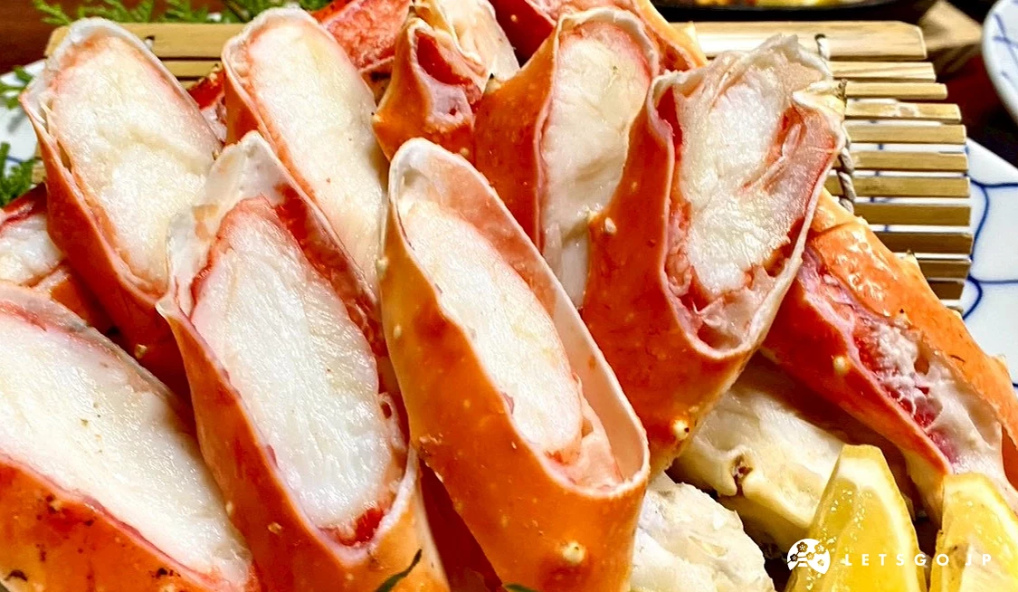 鱈場蟹肉的近距離特寫,展示其分明的肌肉纖維與濕潤的光澤感,背景隱約可見其他日式料理餐盤。