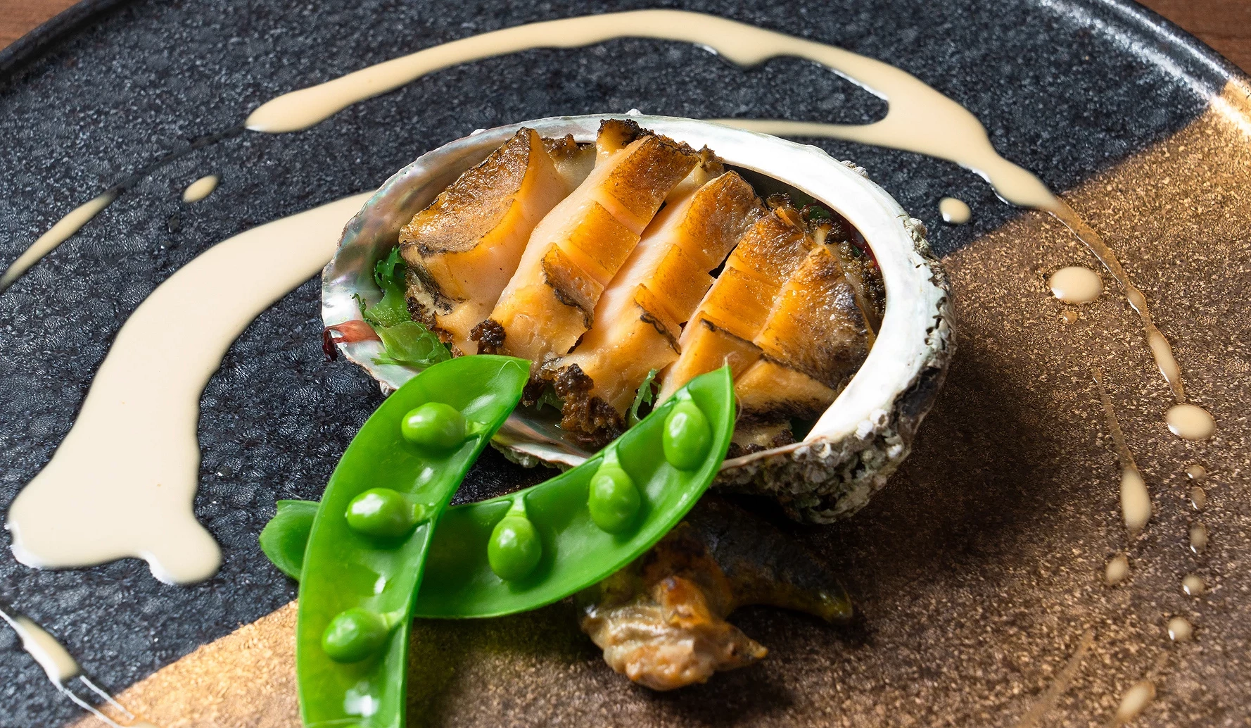 盤上擺放黑鮑魚與豌豆