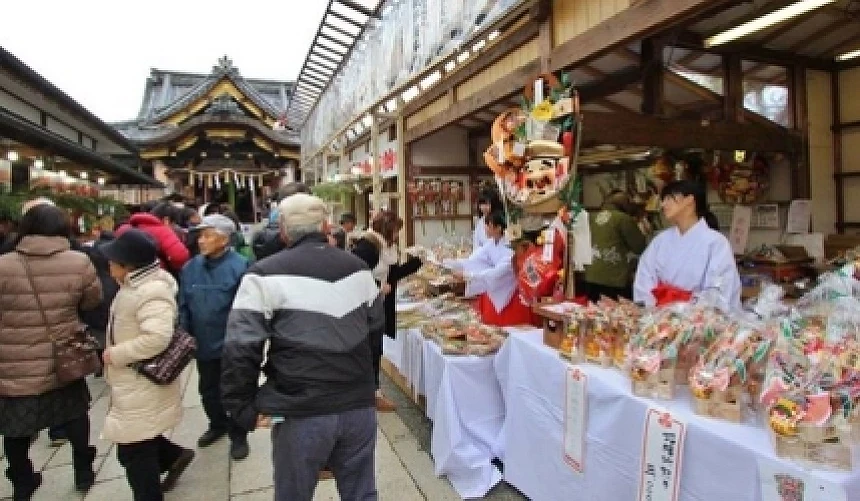 神社境內市集攤位,巫女販售商品,後方可見傳統社殿建築