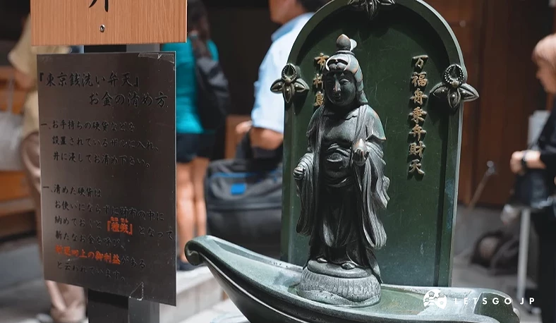 畫面呈現站立在小船上的弁財天神像特寫,神像莊嚴地立於水池中央。