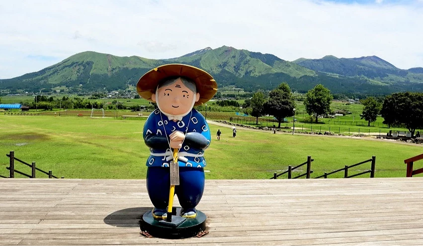 ASO望之鄉久木野的農婦公仔,背後可一覽壯麗的阿蘇連峰絕景