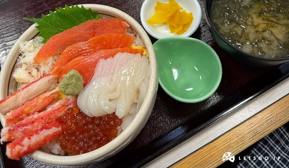 北海道海鮮丼,鋪有鮭魚、蟹肉、花枝與鮭魚卵,搭配味噌湯與小菜