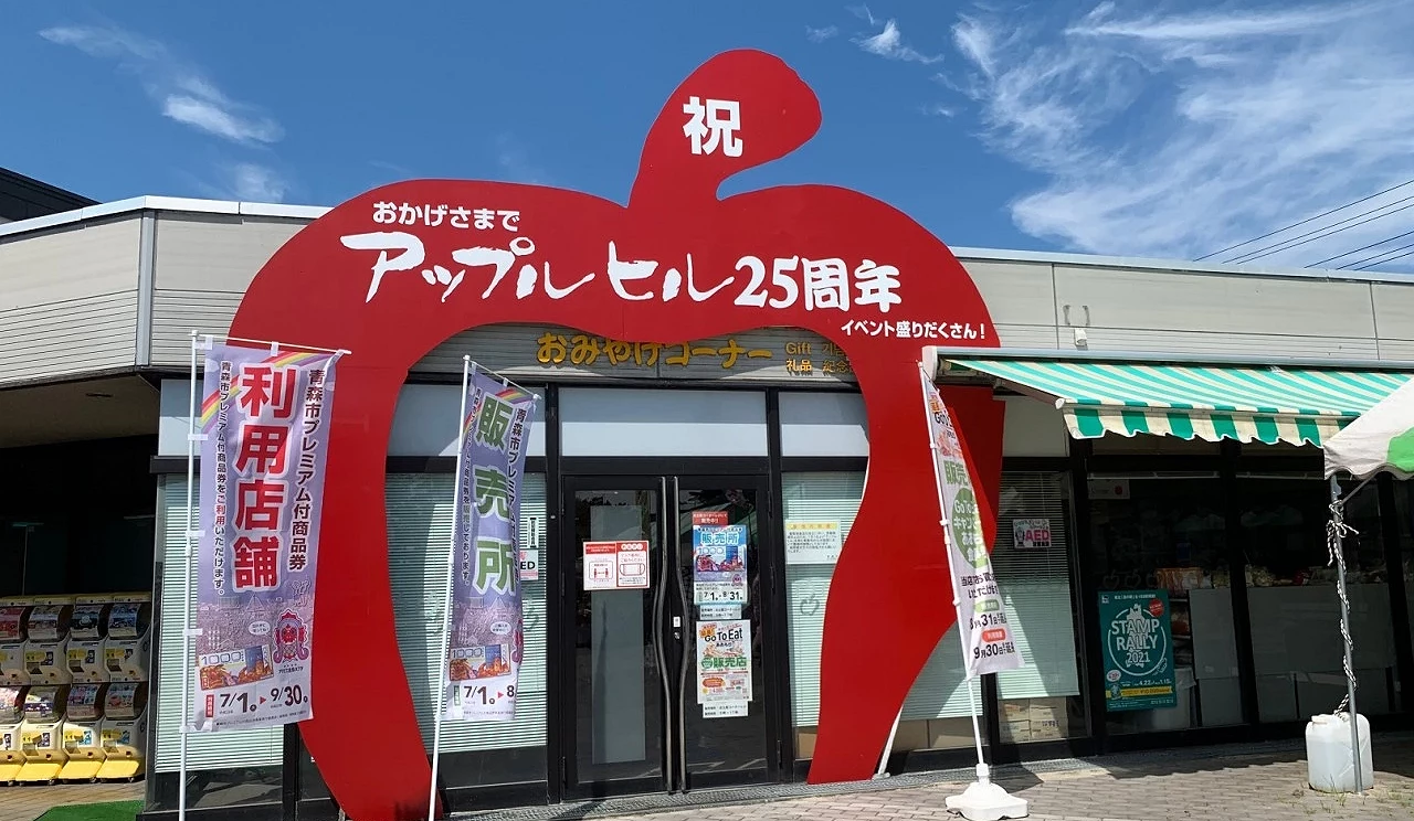 道之驛浪岡 Apple Hill 的入口設計成大型紅色蘋果造型拱門,前方設有旗幟與商店入口,為青森知名觀光與伴手禮採買地點