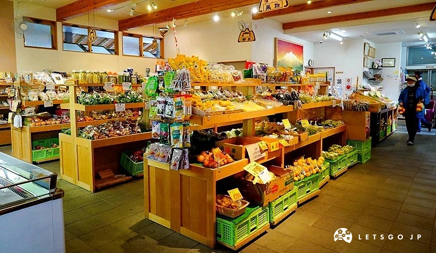 室內農產品直賣區陳列多種青森在地蔬果與加工食品,木製展示架整齊擺放商品,供遊客選購