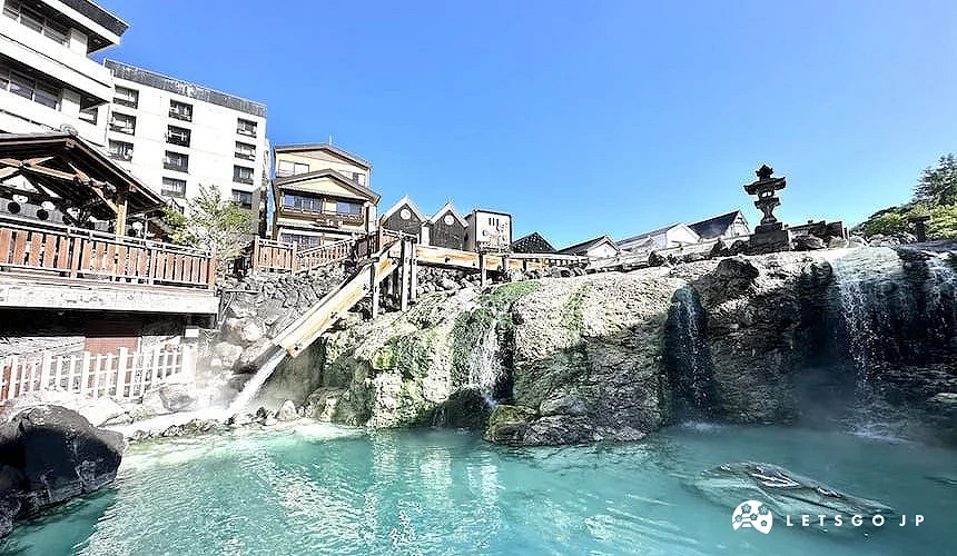 草津溫泉湯畑,溫泉水流經木製設施並匯入池中的景象
