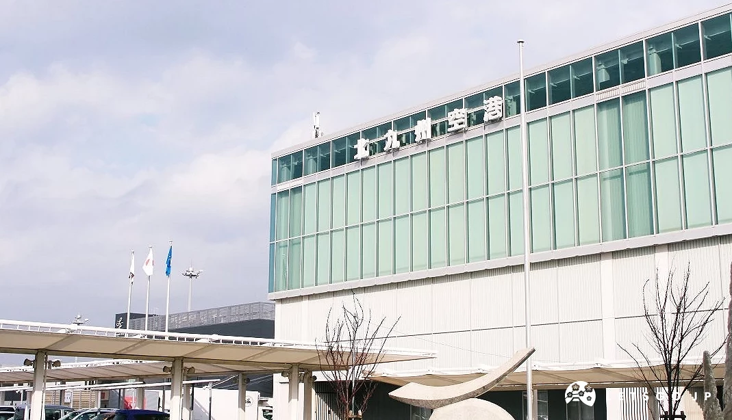 北九州機場航廈外觀,建築採大面積玻璃帷幕設計,前方設有旗桿與車道