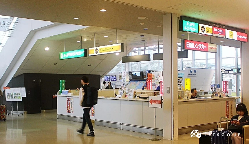 北九州機場航廈內的租車服務櫃台區,可見多家租車公司櫃位與旅客辦理手續的畫面