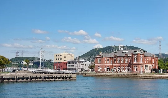 門司港港區景色,紅磚歷史建築臨海而立,遠方可見關門海峽與山景