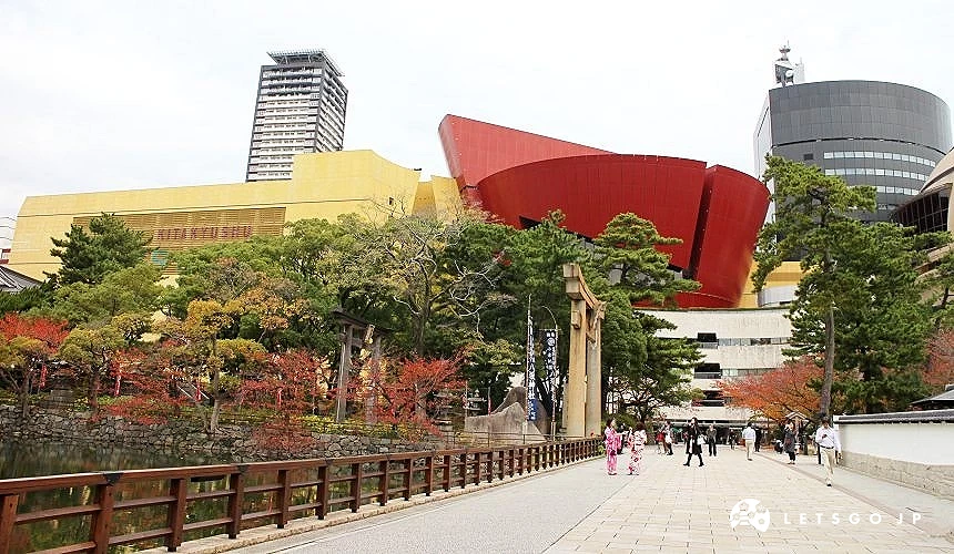 小倉城周邊步道與鳥居,背景為現代建築與商場,呈現新舊融合街景