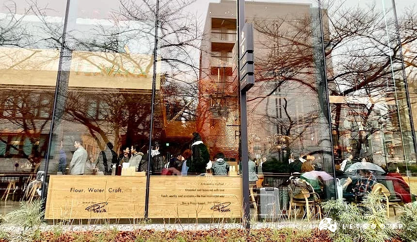 透過玻璃窗可見店內用餐人潮與戶外街景倒影交錯的畫面