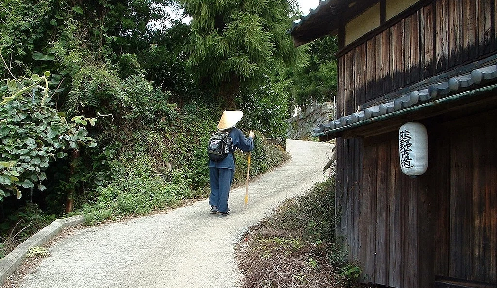 一個人走在小徑上旁邊有熊野古道燈籠