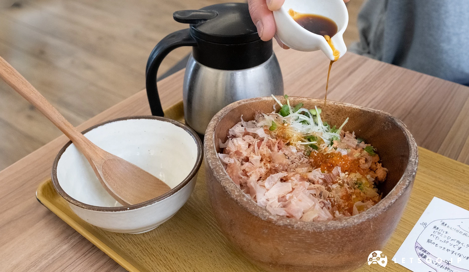 手拿著醬汁在鮭魚丼飯上