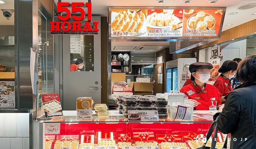 551 HORAI 實體門市,紅色招牌下有穿著紅色制服的店員與玻璃展示櫃