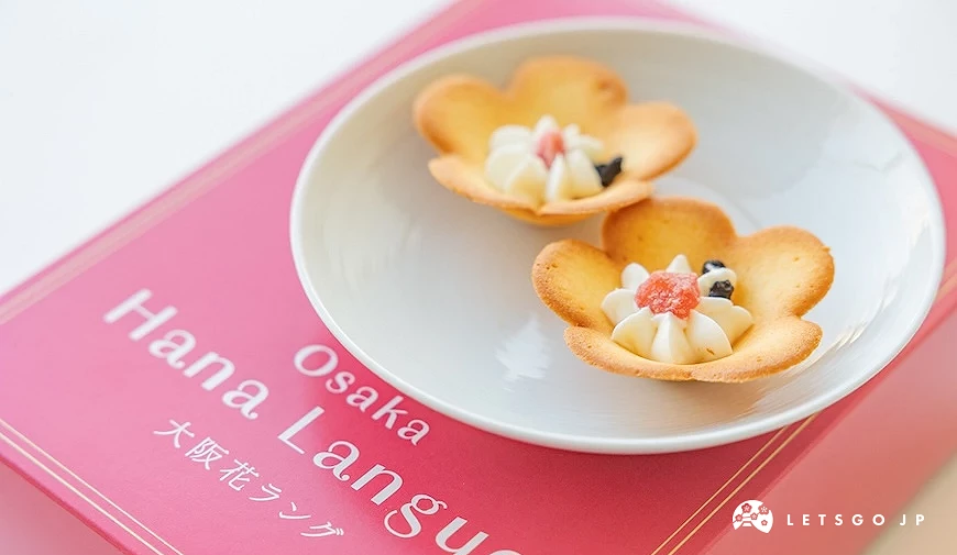 兩塊立體花朵造型餅乾放在白色圓盤上,中間點綴奶油與果乾