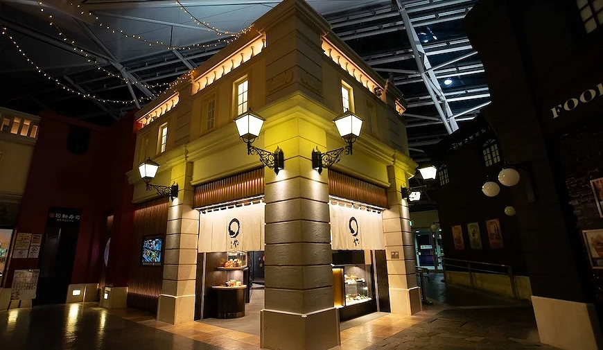 室內仿街道商場空間,黃色歐式建築風格店舖,門口掛有寫有日文標語的白色暖簾