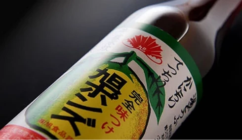 玻璃瓶身特寫,白色標籤上印有旭ポンズ字樣與黃色柑橘圖案
