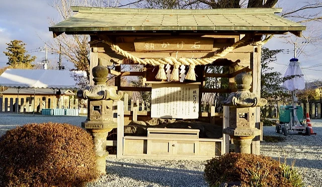 阿蘇神社願掛石,石造祈願處上方掛有注連繩與願かけ石匾額,兩側設有石燈籠