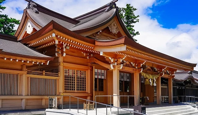 熊本縣阿蘇神社的木造拜殿側面,屋頂線條優美,前方設有參拜階梯與無障礙坡道