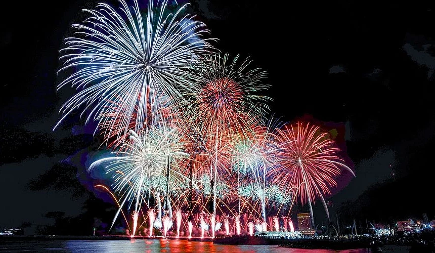 熱海海上花火大會於夜晚舉行,多彩大型煙火在海灣上空綻放,海面映照煙火光芒
