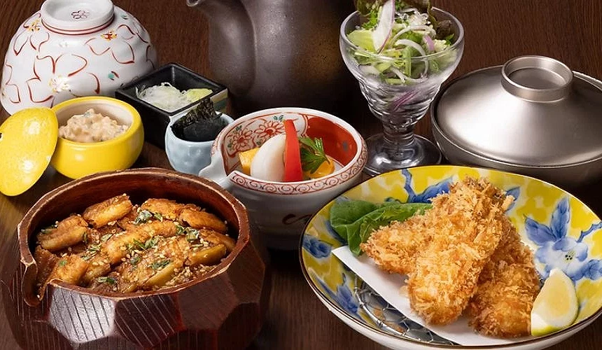 餐桌上擺放田里津庵的星鰻飯與炸物套餐,木桶中盛有星鰻飯,旁邊可見炸物、小菜、沙拉與茶壺