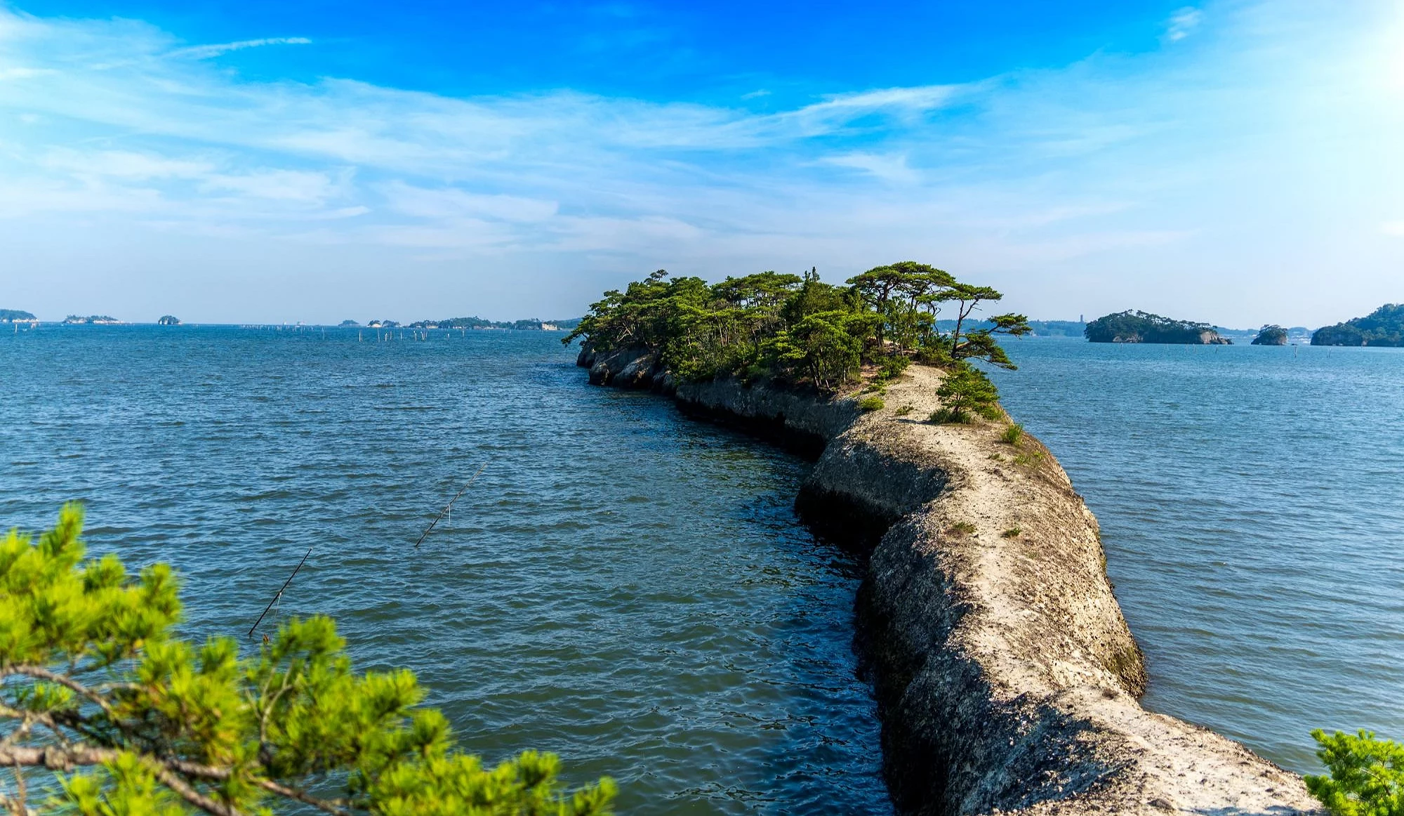 宮城縣松島灣的馬之背狹長岩石地形延伸至海面,岩上長有松樹,兩側可見藍色海灣與遠方島嶼