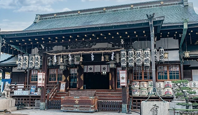 大阪天滿宮本殿建築正面,木造結構與綠色屋頂,前方設有賽錢箱與參拜空間