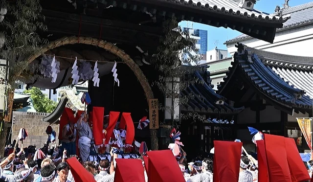 大阪天滿宮天神祭活動現場,人群聚集進行傳統儀式,抬神轎通過神社入口
