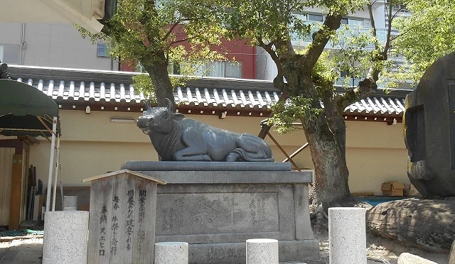 大阪天滿宮撫牛雕像,石座上臥牛造型,參拜者會觸摸祈求學業與身體健康