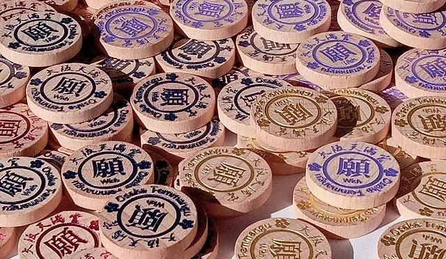 大阪天滿宮許願幣特寫,圓形木製硬幣印有不同顏色與圖案