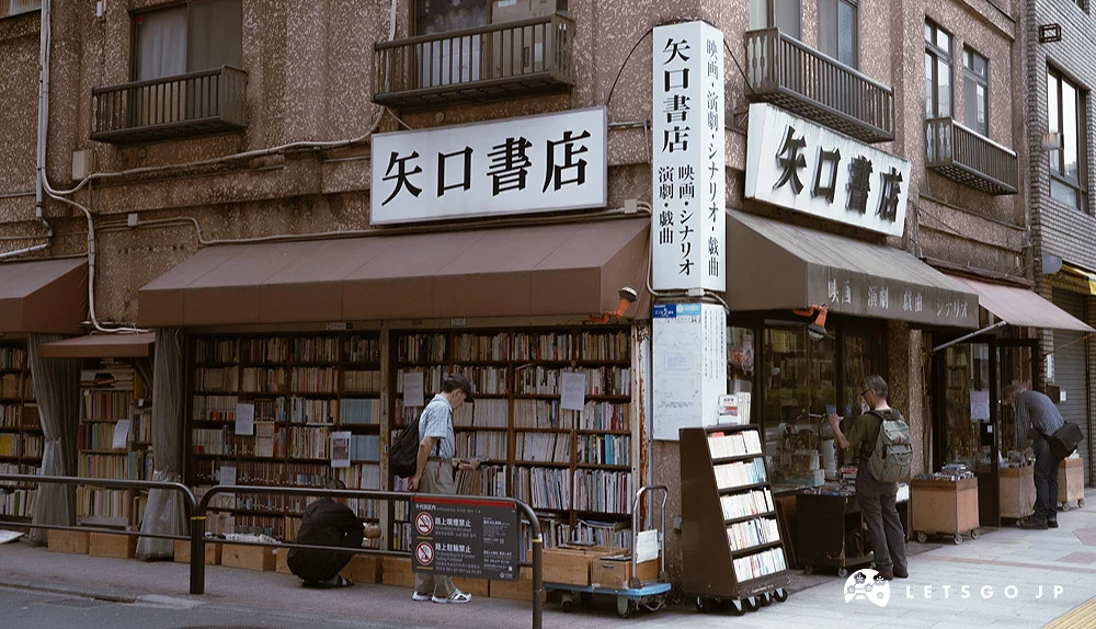 以矗立於轉角處的老木造建築為背景,與整面滿載古舊書籍的露天書牆與顯眼的白底黑字招牌,呈現矢口書店的懷舊景觀特徵