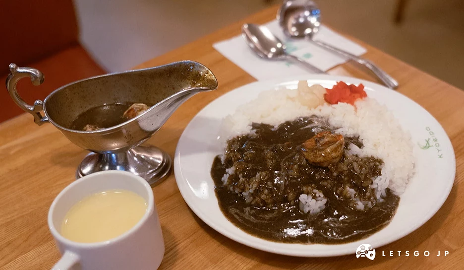 以裝在復古銀色醬汁盅內的深咖哩醬汁與白飯為背景的咖哩飯